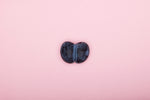Black kidney-shaped stone on a pink background, perfect for decorative use.
