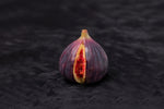 Fresh fig with a vibrant red interior and purple skin, showcasing its juicy texture.