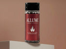 Allume libido capsules in a clear bottle with a red label featuring a flame logo.
