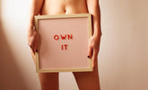 Person holding a sign with 'OWN IT' related to unlocking the secrets of enhanced intimacy with Liquid Vibrator Sweet Fig 20 ml.