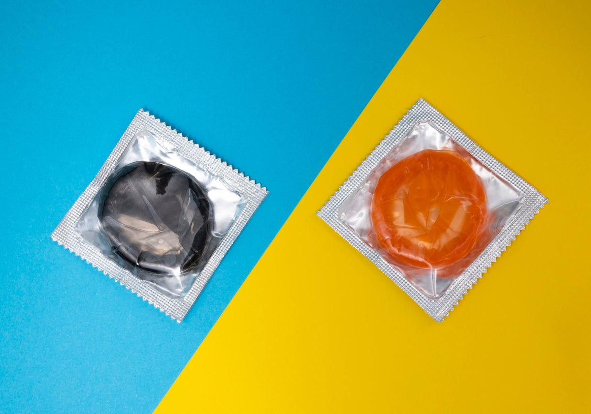 Colorful condoms in black and orange packaging on a blue and yellow background.