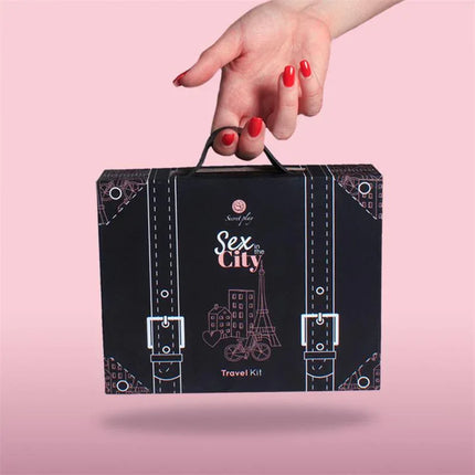 Hand holding Travel Kit Sex in the City box against a pink background.