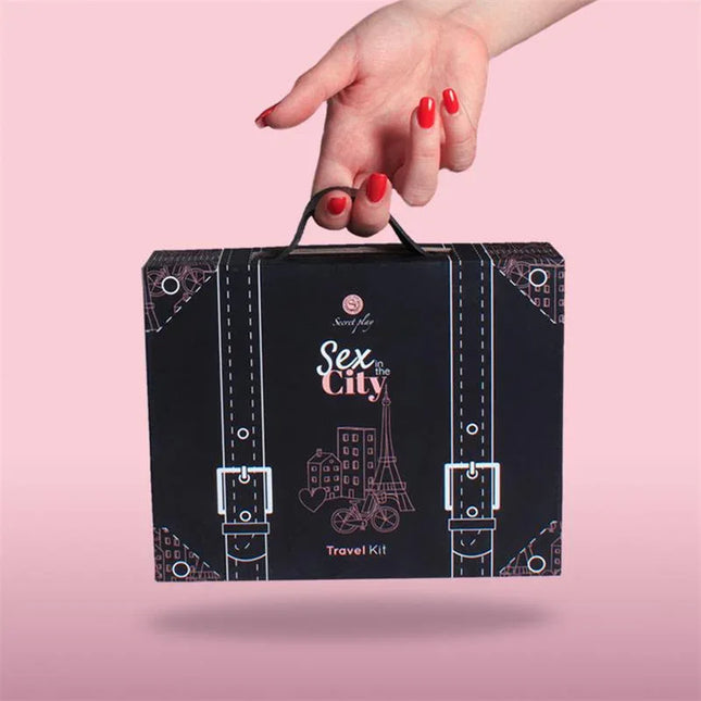 Hand holding Travel Kit Sex in the City box against a pink background.
