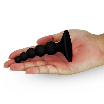 Hand holding Butt Plug Lure Me Silicone Black with beaded design and suction cup.