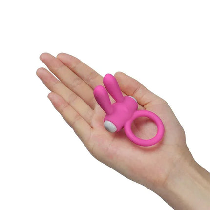 Hand holding Vibrating Cockring Power Clit Pink, a silicone ring with rabbit-ear clitoral stimulator for couples' intimacy.