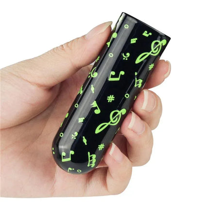 Hand holding Vibrating Bullet Glow-in-the-dark with music notes design, compact size for easy travel and fun in low light conditions.
