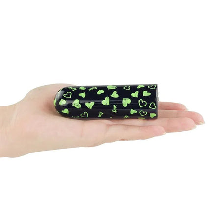 Vibrating Bullet Glow-in-the-dark compact USB-rechargeable device held in hand with glowing hearts design, perfect for discreet travel use.