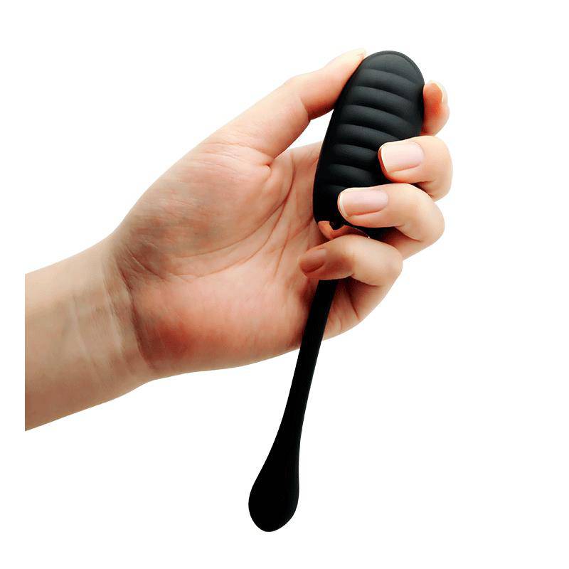 Black ribbed silicone kegel ball with a long flexible tail held in hand.