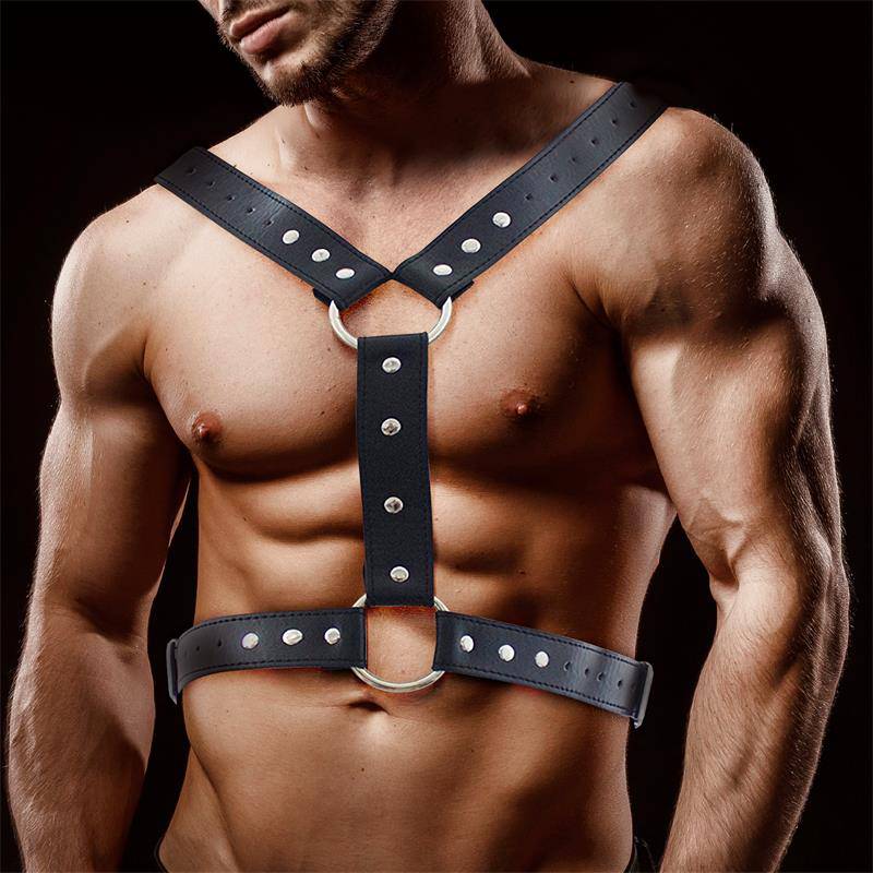 Black vegan leather male chest bondage harness with silver rivets and metal ring details.
