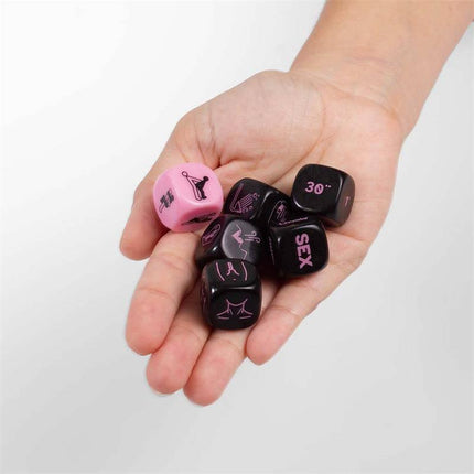 Hand holding 6 Die Play Sex Game (ES/EN/DE/FR/NL/PT/IT) dice set with pink and black dice.