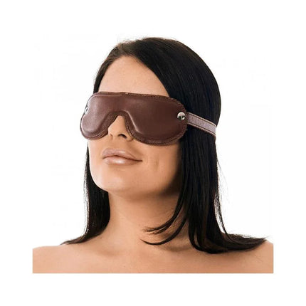Person wearing a brown leather blindfold with padded interior and adjustable strap, ideal for sensory deprivation and role play.