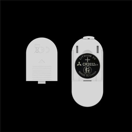 CR2032 3V lithium battery and battery compartment cover on a black background