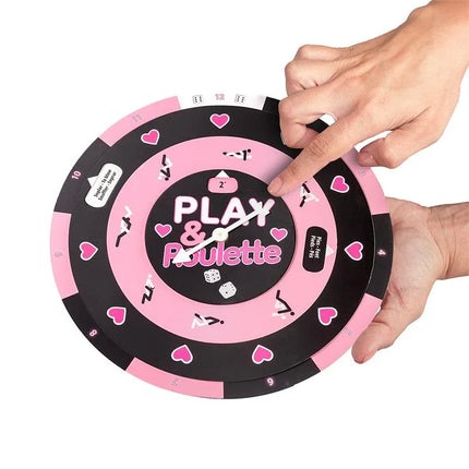 Hands holding a Play & Roulette (ES/PT/EN/FR) table game with a pink and black design for enhancing romantic experiences.