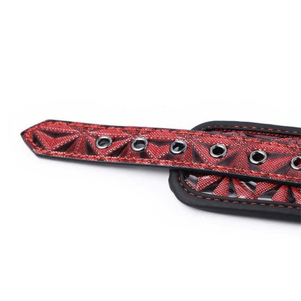 Close-up of Adjustable Padded Handcuffs Diamond Vegan Leather with red detailing.