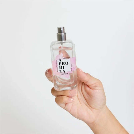 Hand holding Afrodita Natural Pheromones Perfume Spray 50 ml bottle with pink label for attracting allure and confidence.