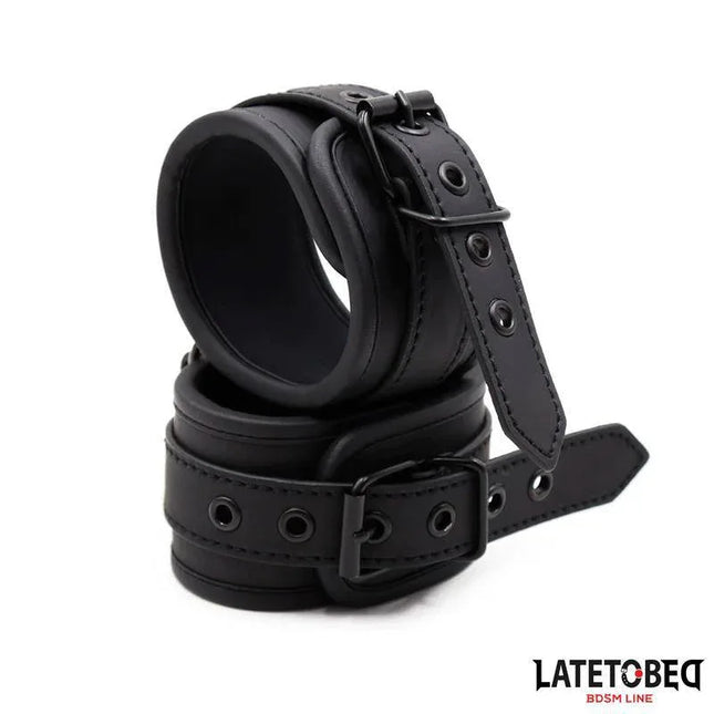 Ankle Cuffs BDSM - Solid Black made of PU and metal with adjustable straps for secure restraint, available from Latetobed.