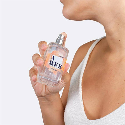 Person holding Ares Natural Pheromones Perfume 50 ml spray bottle, showcasing an elegant fragrance engineered for attraction.