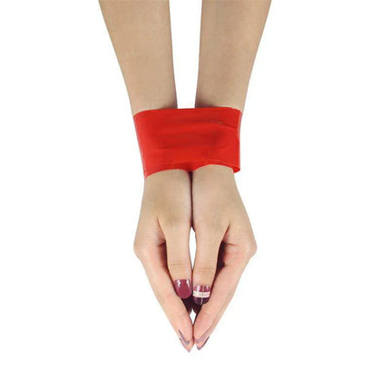 Hands bound with Bondage Tape Non Sticky Red for playful restraint.