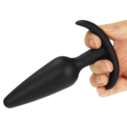Hand holding Butt Plug Lure Me Size S Black with an anchor base, made of body-safe silicone for beginners.