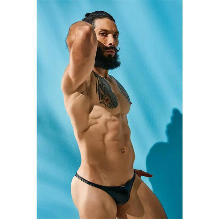 Man wearing C4M11 Brazilian Brief Leatherette Black against blue background, showcasing the bold, contemporary design by CUT4MEN.