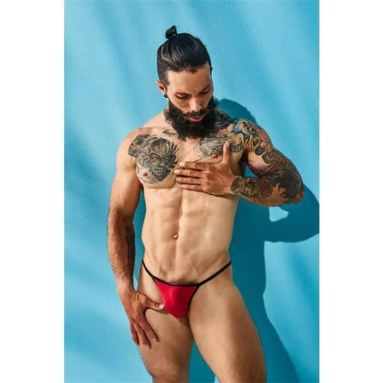 C4M12 Briefkini RedOTS worn by a tattooed model against a blue background, showcasing modern men's bold and comfortable underwear design.