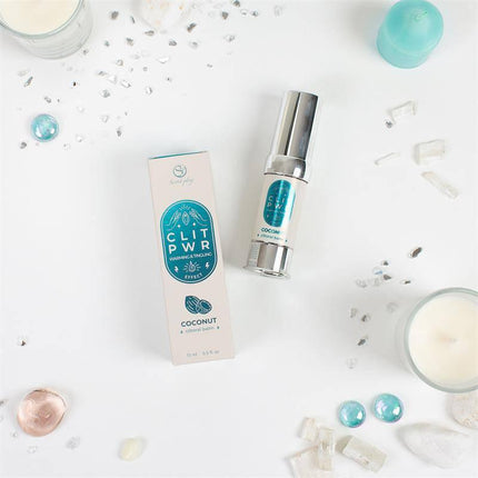 Clit Pwr Clítoris stimulating balm Coconut 15 ml with packaging, surrounded by decorative stones and candles.