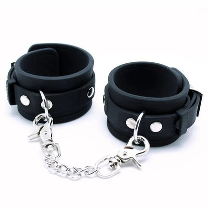 Black silicone cuffs with metal chain for bondage play, adjustable with buckles. Focus keyword: Cuffs Silicone.