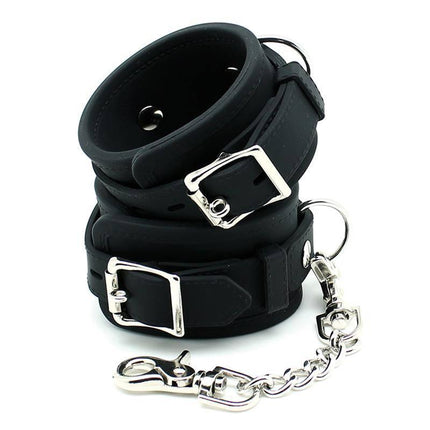 Rimba Bondage Play Cuffs Silicone with metal chain, black silicone material, 5.5 cm width, adjustable buckles, sleek durable design