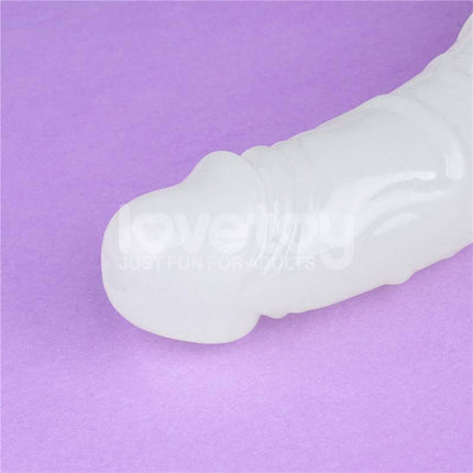 Close-up of Double dildo Lumino Blue Light 18.5 glowing in the dark on a purple background, showcasing dual-end design for versatile use.