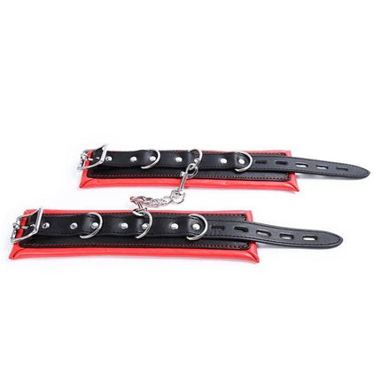 High performance ankle cuffs with black leather, red padding, and metal buckles for secure fit and ring attachment for versatility.
