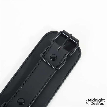 Close-up of Midnight Desires' Hogtie Cross Bar Hand and Ankle Cuffs showing vegan leather and buckle detail.