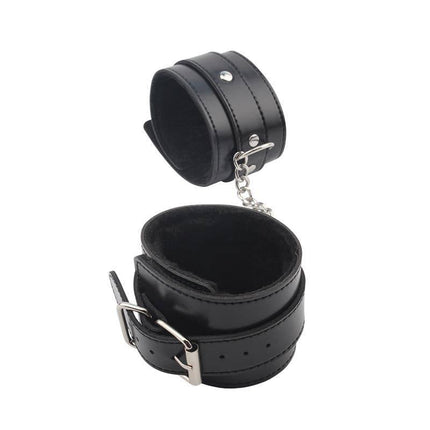 Black wrist restraints from Kit Restrain You Lover Silicone for adult play, featuring adjustable straps and sturdy metal chain for secure fit.