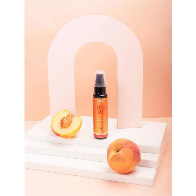 Lick Me Peach Kissable Gel with Warm Effect 50ml bottle displayed with fresh peaches, enhancing intimacy and flavor.