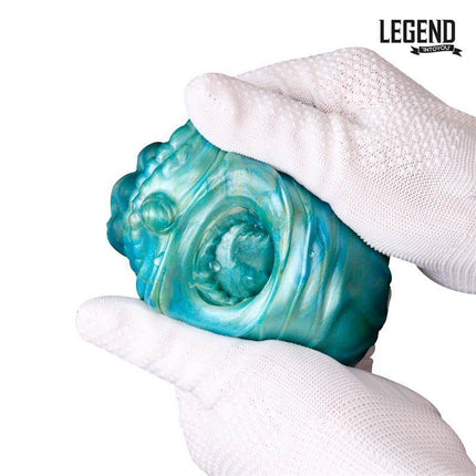 Gloved hands holding the Mouthor Male Masturbator Liquid Silicone 16 cm with textured blue design.