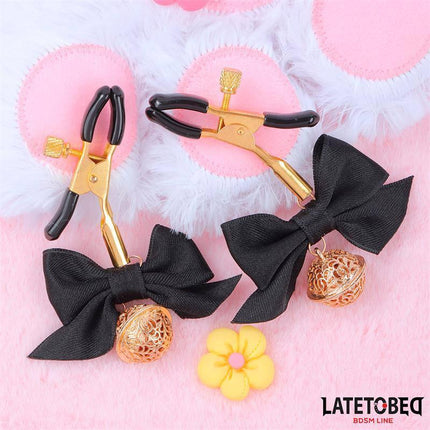 Nipple clamps with Bow Black featuring adjustable clamps with black bows and gold bells, part of the Latetobed BDSM Line.