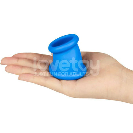 Hand holding blue Pinnacle Pro Tapered Squeeze Stretcher Penis Ring for enhanced comfort and sensation