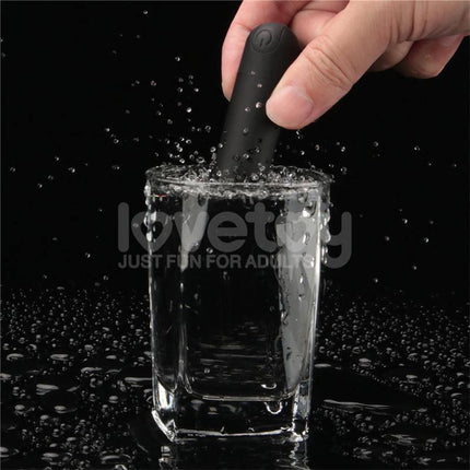 Hand holding a black vibrating bullet submerged in a glass of water, showcasing waterproof design for Printed Vibrating Sexy Panties 34-38.
