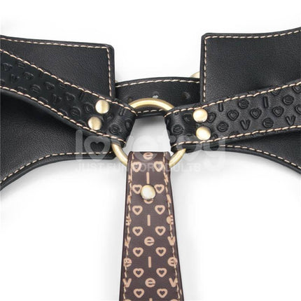 Close-up of Rebellion Reign Full Body Harness in premium PU faux leather with gold accents and heart patterns.