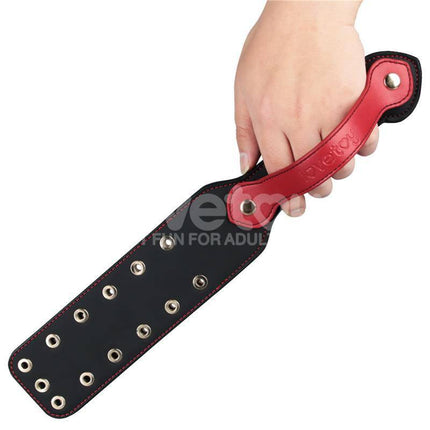Hand holding Rebellion Reign Paddle Dual-Branch 15 with durable PU and red handle for intimate play.