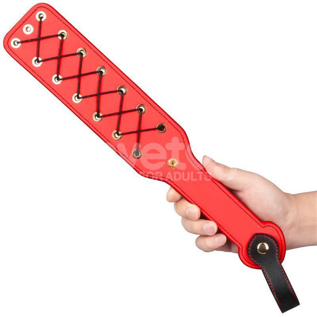 A hand holding the Rebellion Reign Rope Paddle 15 with distinctive red and black crisscross rope design for heightened sensations.