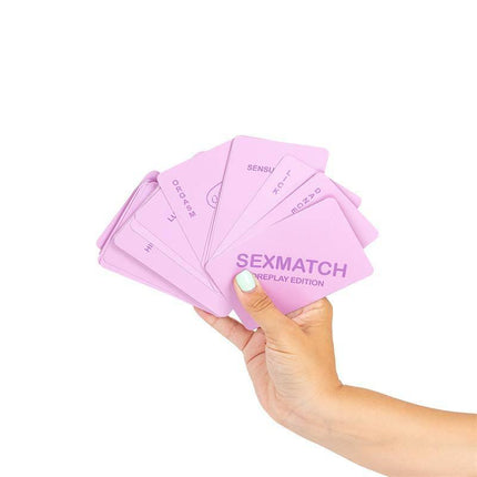 Hand holding Sexmatch Game Foreplay Edition cards, showcasing various card designs in a fan arrangement.