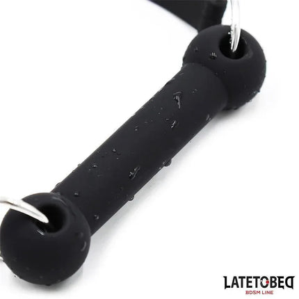 Close-up of a black Silicone Bone Gag Adjustable with water droplets, emphasizing its body-safe silicone material and sleek design.