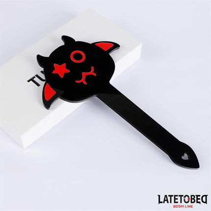Spanking Paddle 25.2 cm from Latetobed BDSM Line with devil design, black and red colors, PVC construction, placed on white box.