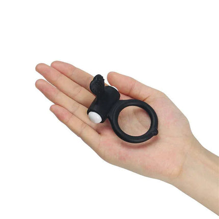 Vibrating Cockring Power Clit Black silicone ring with clitoral stimulator held in hand for couples' intimacy and shared pleasure.