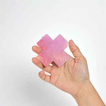 Hand holding Wow Boobs! Nipple Covers Cross Shapped Holografic with holographic shine, perfect for festivals and special occasions.